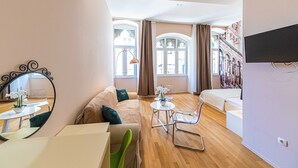 A modern hotel room with a sofa, a small round table, a chair, and a bed. - Pjaca City Rooms (Split)