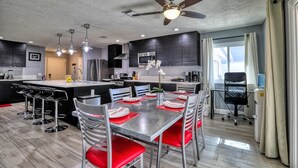 A modern kitchen with a central island, bar stools, and a dining table set for four. - Fully licensed pool home w/outdoor kitchen. (Las Vegas)