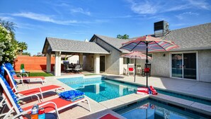 A backyard with a swimming pool, lounge chairs, and an umbrella. - Fully licensed pool home w/outdoor kitchen. (Las Vegas)
