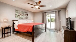 A bedroom with a bed, a ceiling fan, a TV, a nightstand, and a window with curtains. - Fully licensed pool home w/outdoor kitchen. (Las Vegas)