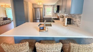 Una cucina moderna con un'isola grande, elettrodomestici in acciaio inossidabile e una schiena di pietra.