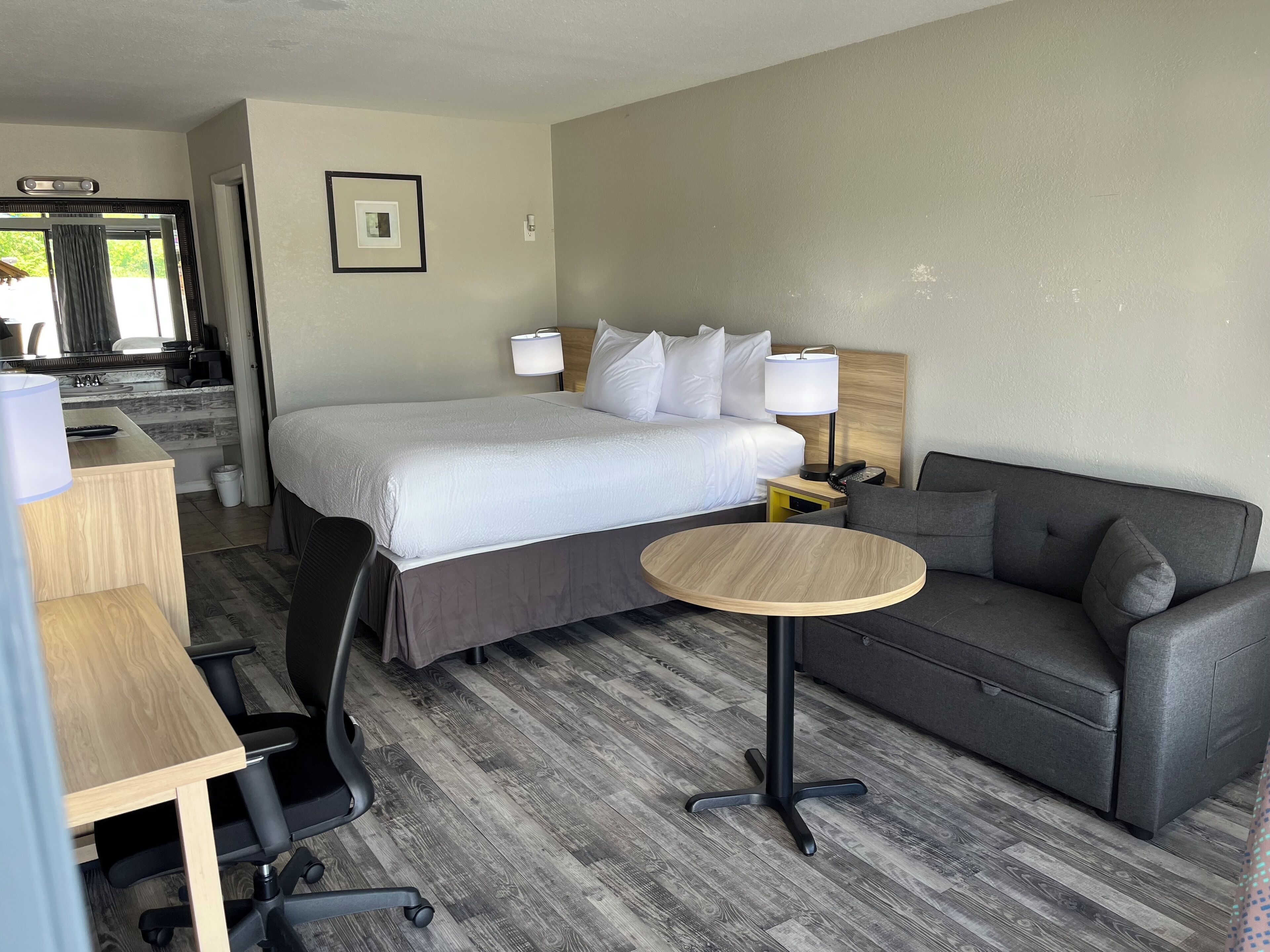Een hotelkamer met een bed, een slaapbank, een bureau en een stoel.