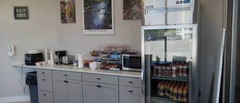 A kitchenette with a coffee maker, toaster, microwave, and a refrigerator stocked with beverages.