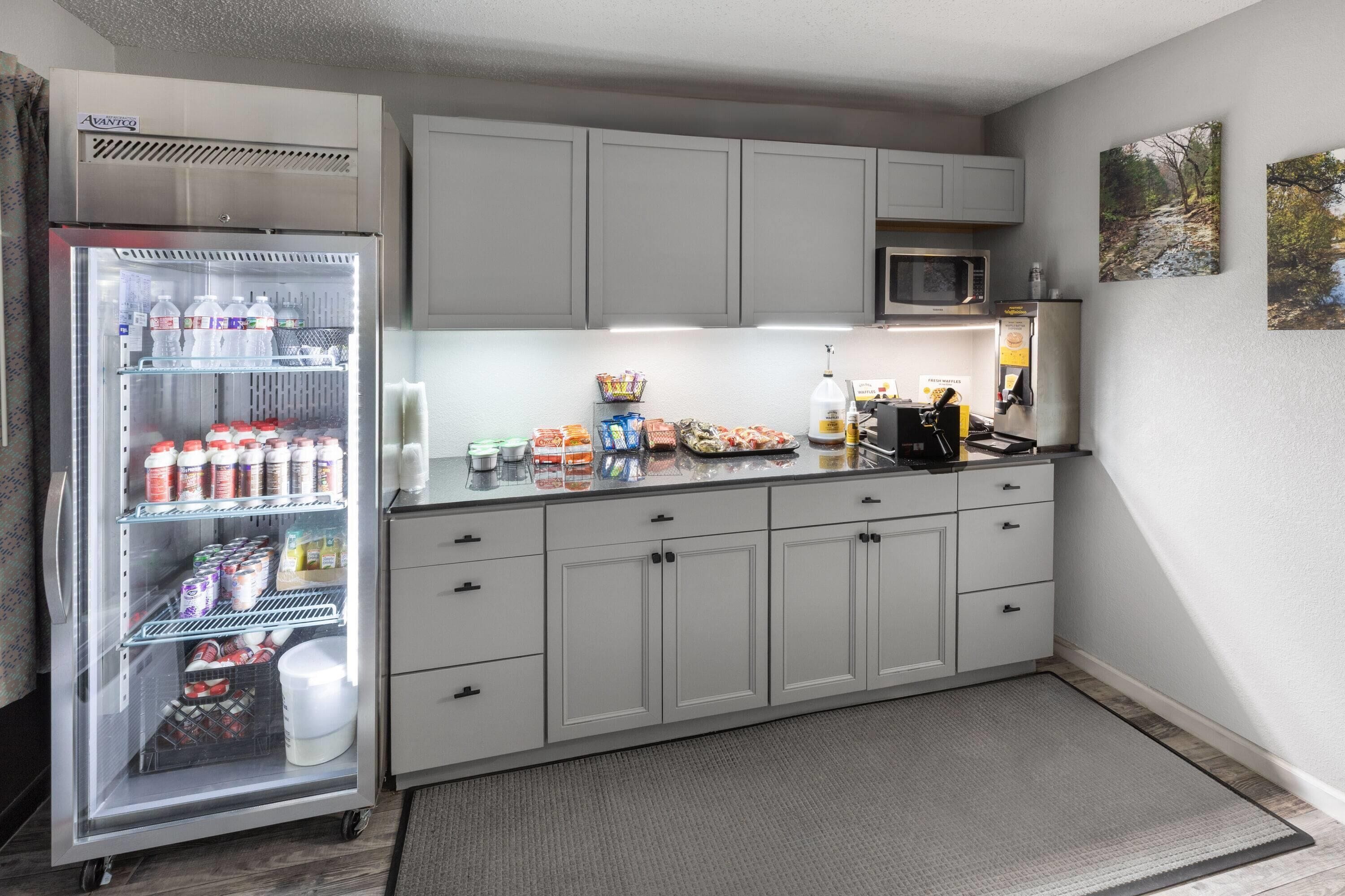A compact kitchen with a refrigerator, microwave, and a small countertop with various items.