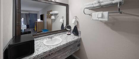 A bathroom with a granite countertop, a sink, a mirror, and a towel rack.