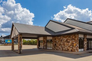 A Days Inn with a stone facade, covered parking, and a clear blue sky.