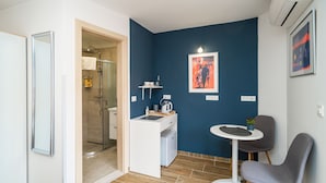 A compact room with a shower, a small kitchenette, a chair, and a table. - Argenta Rooms - Premium Double Room with Balcony (Dubrovnik)