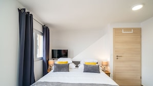 A bedroom with a large bed, two bedside tables with lamps, a television, and a wooden door. - Argenta Rooms - Premium Double Room with Balcony (Dubrovnik)