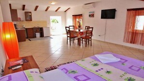 Habitación de hotel con cama, escritorio, silla, mesa de comedor y zona de cocina.