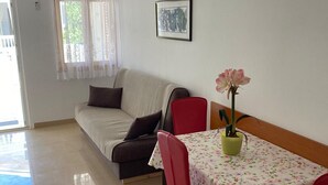 Une pièce comprenant un canapé, une table à manger avec des chaises, une plante en pot et un tableau encadré accroché au mur.