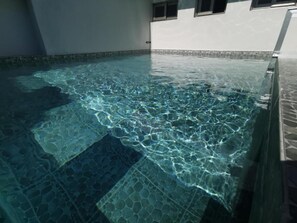 Una piscina interna trasparente, con pavimento e pareti in piastrelle.
