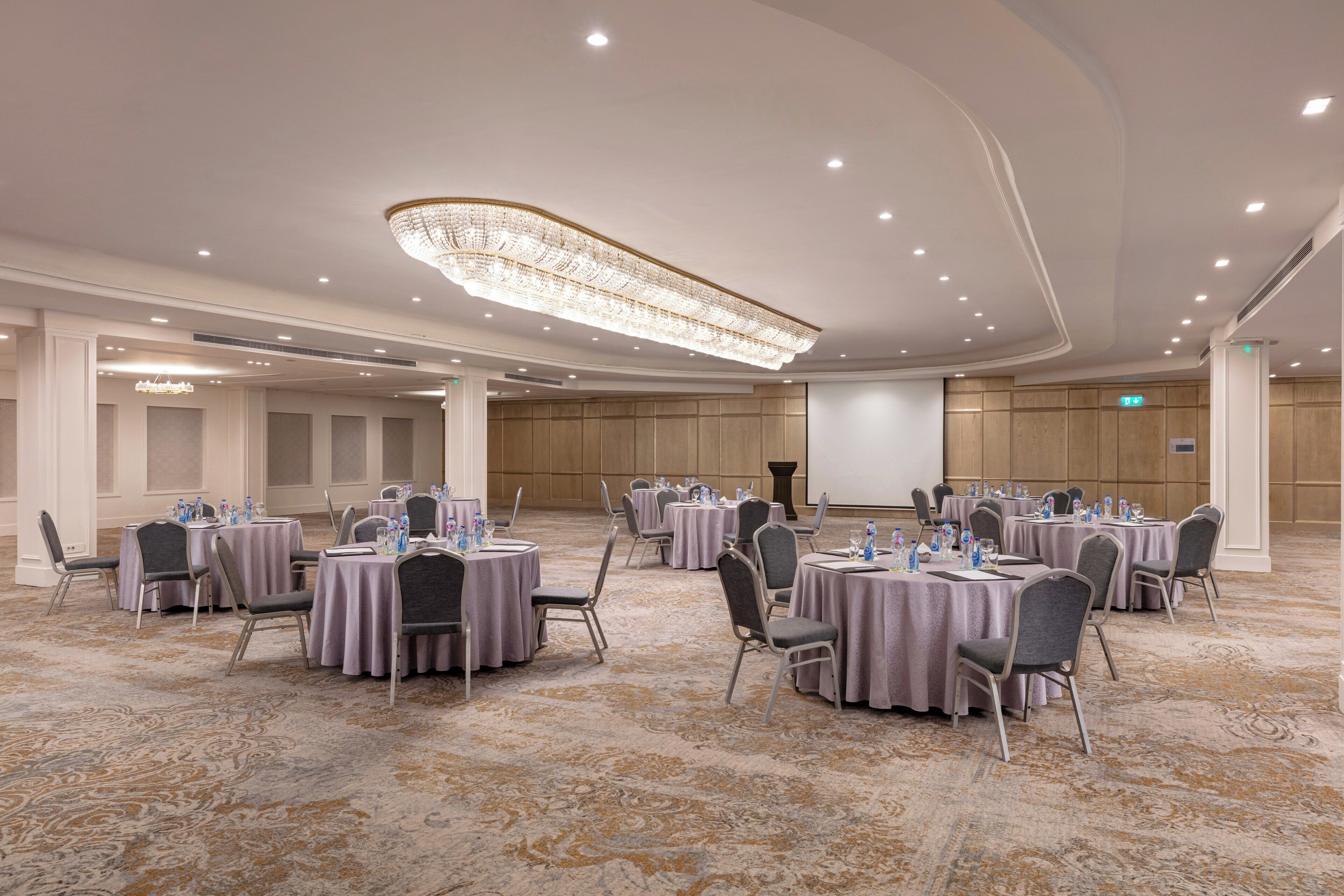 A conference room with round tables, chairs, and a large chandelier.