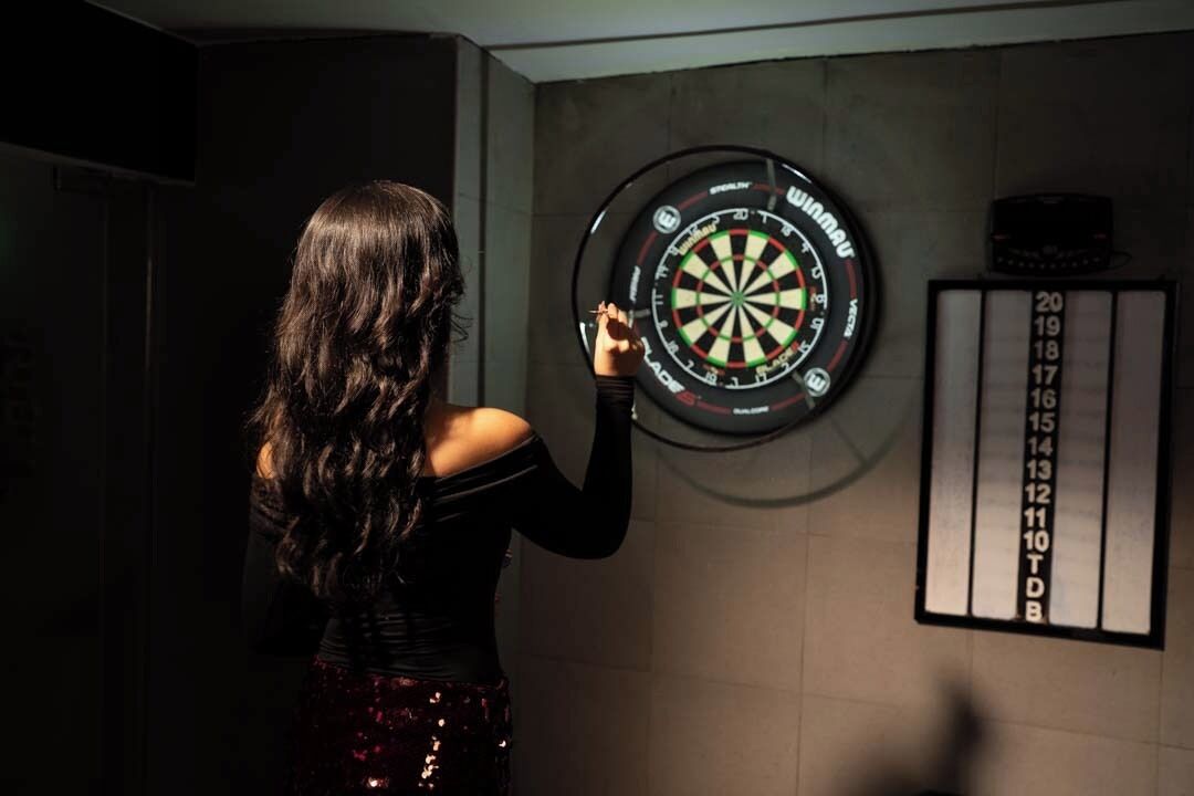 A dartboard mounted on a wall with a scorecard beside it.