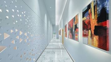 A hallway with a patterned wall and artwork on the right.