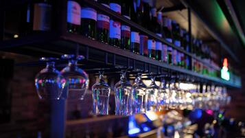 Un bar con estantes llenos de botellas de vino y copas colgando.