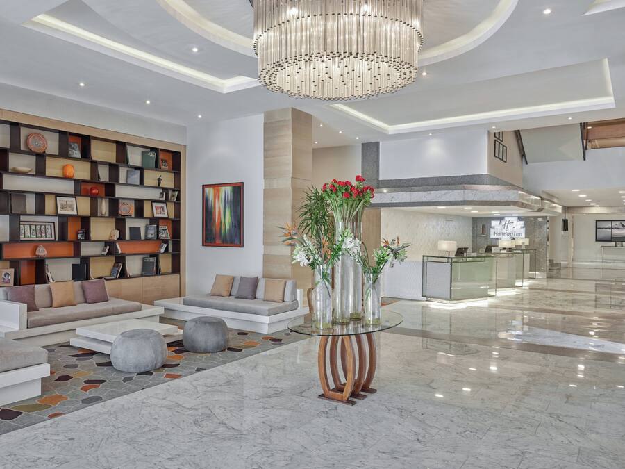 A modern lobby with a seating area, a glass coffee table, and a decorative vase with flowers.