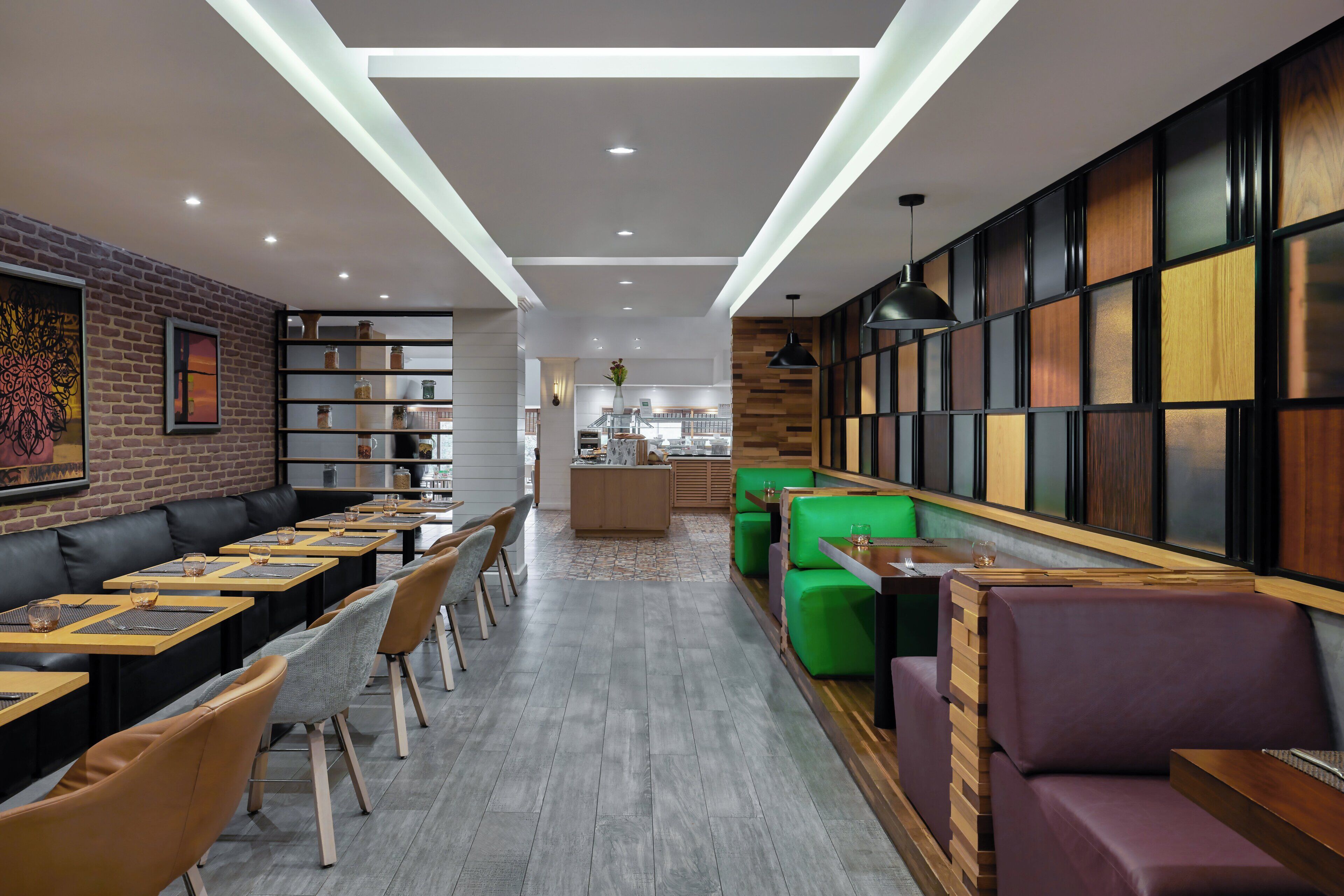 A modern restaurant with a brick wall, wooden panel wall, and green and purple seating areas.