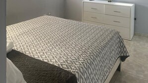 Ein Schlafzimmer mit einem Bett, einer Kommode, einem an der Wand montierten Fernseher und einem Deckenventilator.