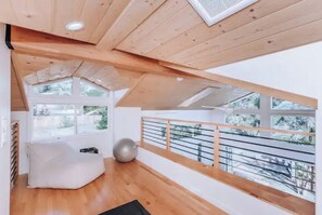 Relax and stay active in this spacious room with a large window offering a view of the outdoors, a balcony, and a bean bag chair.