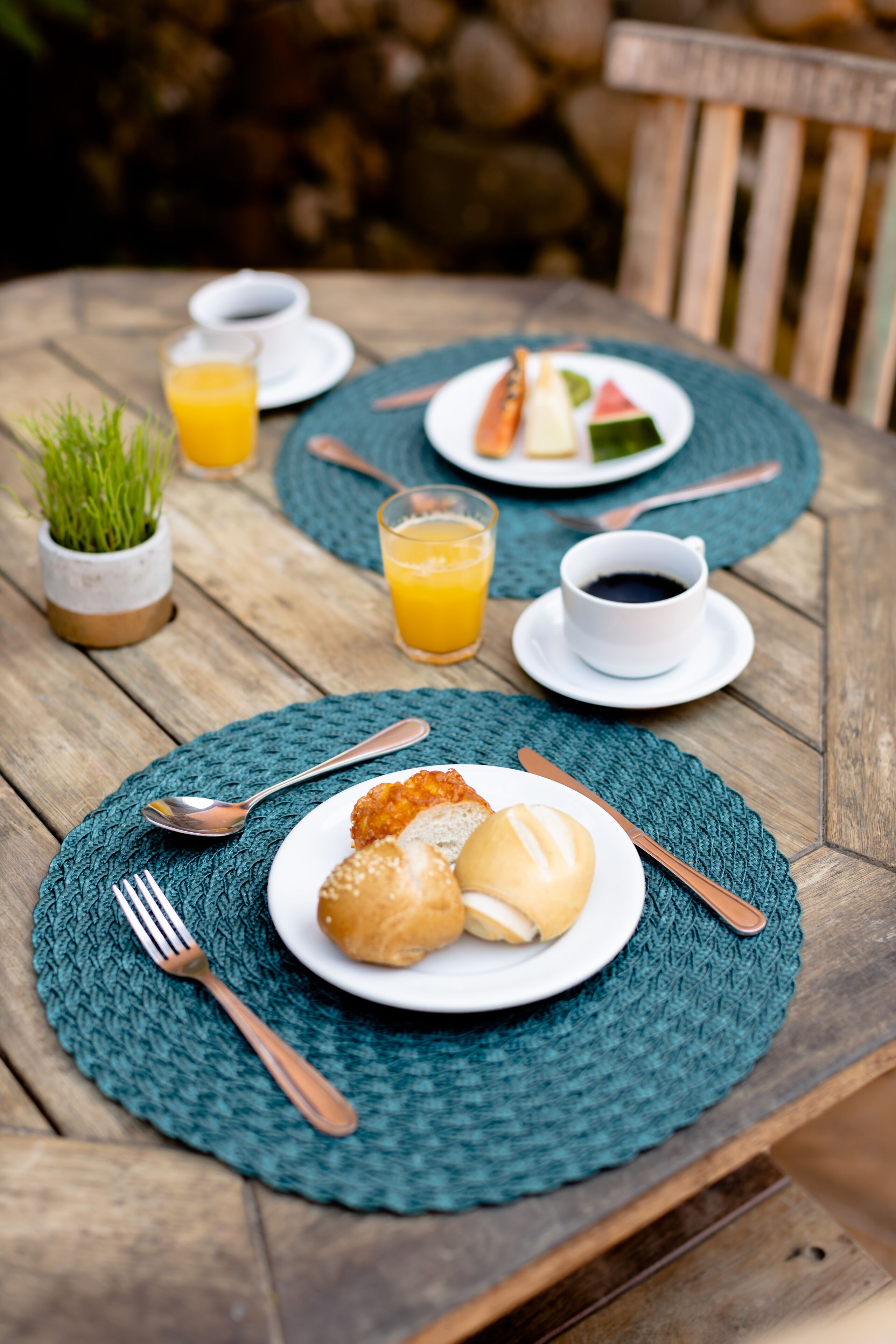 A wooden table set with breakfast plates, utensils, and a cup of coffee.