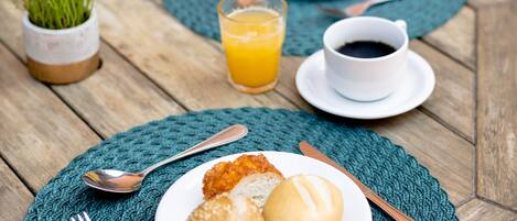 A wooden table set with breakfast plates, utensils, and a cup of coffee.
