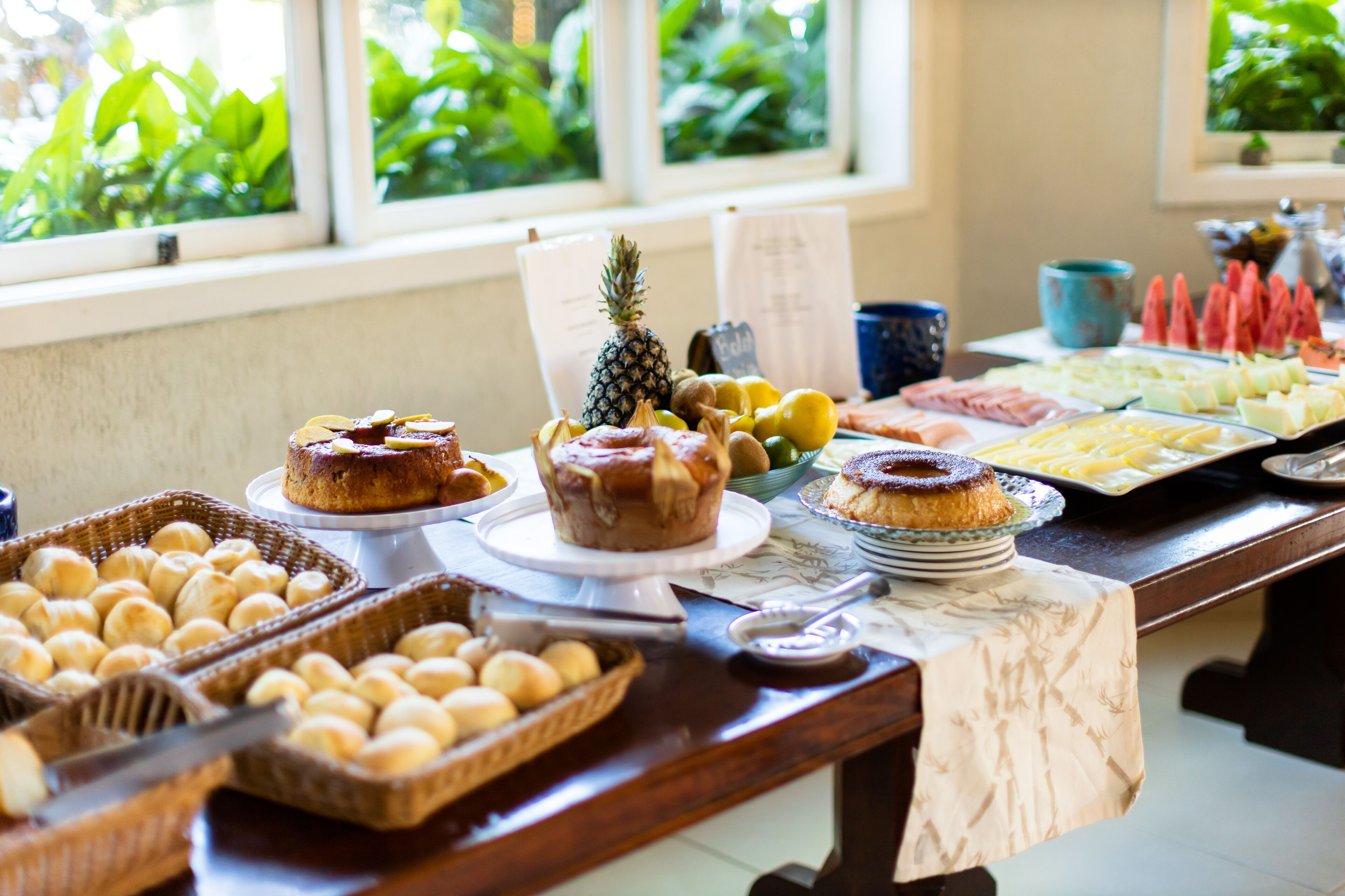 A buffet table with various baked goods, fruits, and a pineapple.