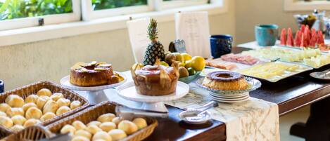 A buffet table with various baked goods, fruits, and a pineapple.