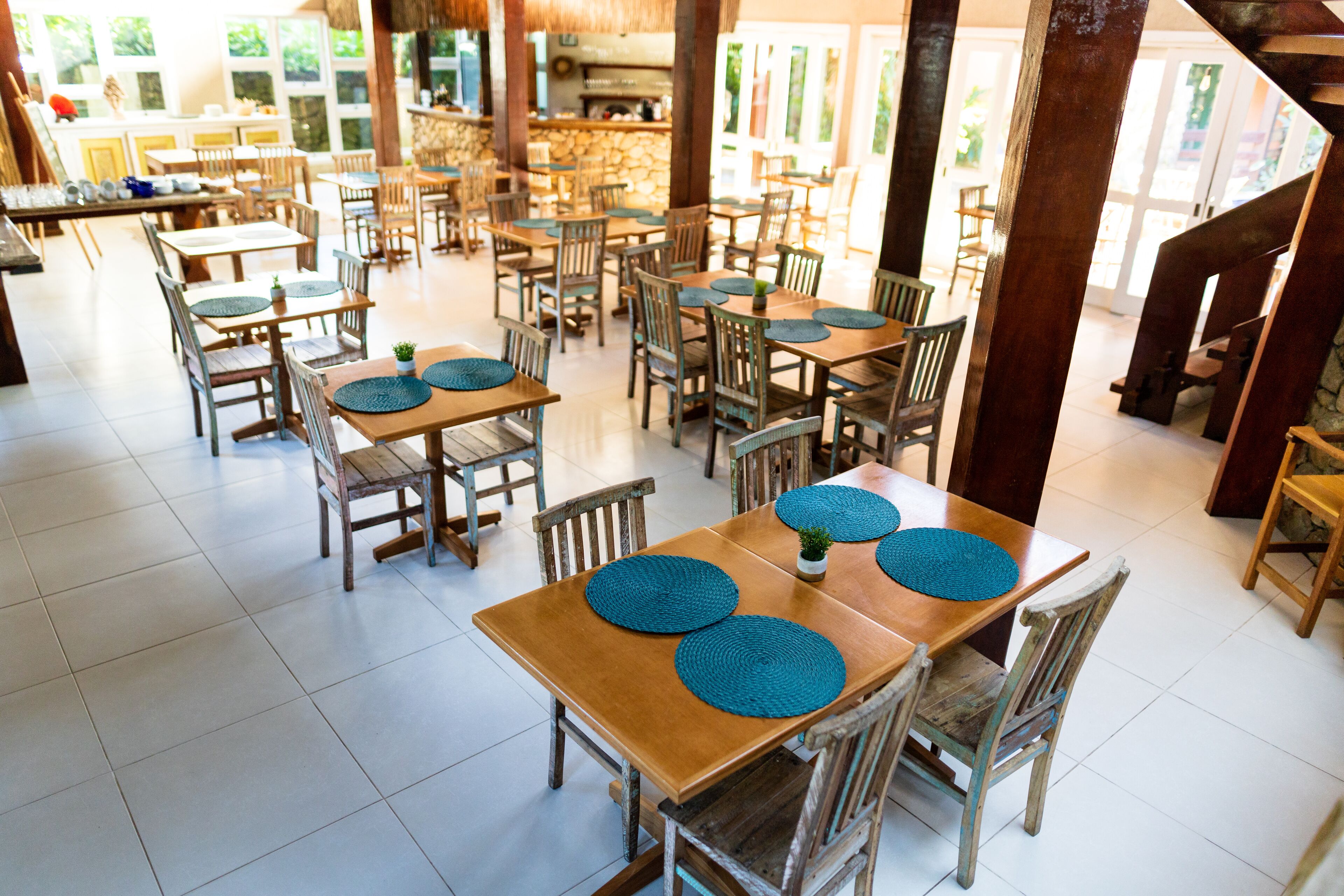 A spacious dining area with multiple wooden tables and chairs, each with a blue placemat.