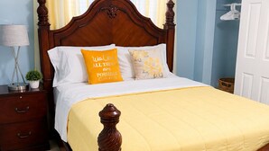 A bedroom with a wooden bed, a nightstand, a lamp, and a window with curtains.