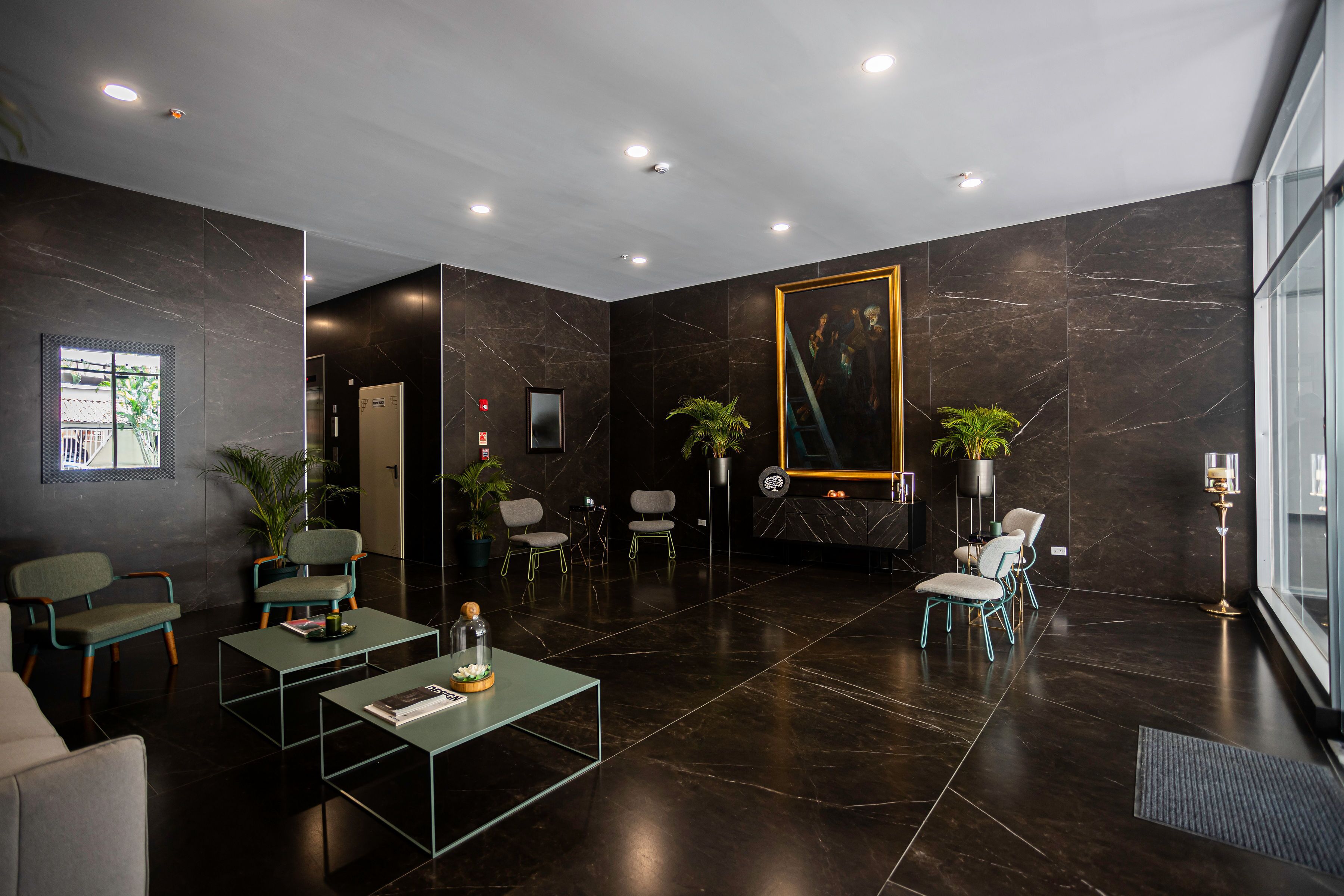 Een moderne lobby met donkere marmeren wanden, zithoeken en een groot schilderij in een lijst.