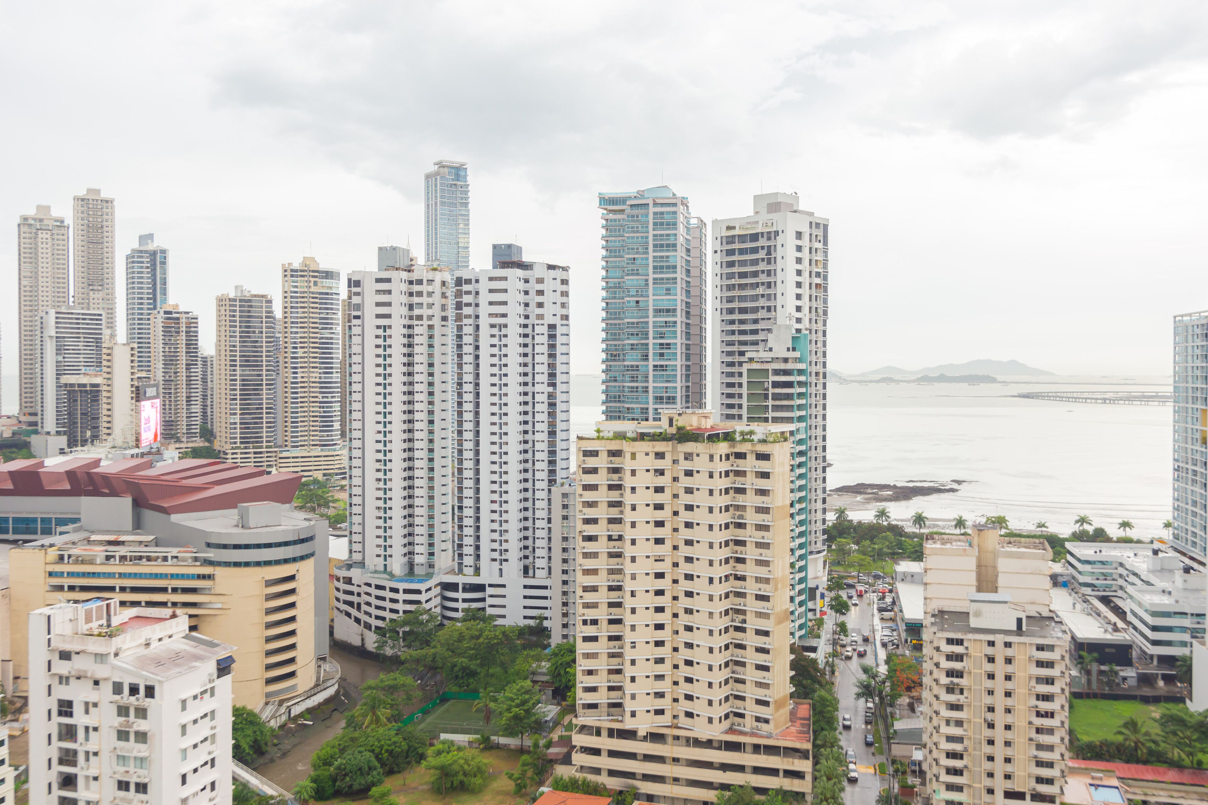 A high-rise building complex with multiple residential and commercial structures, surrounded by greenery and a body of water.