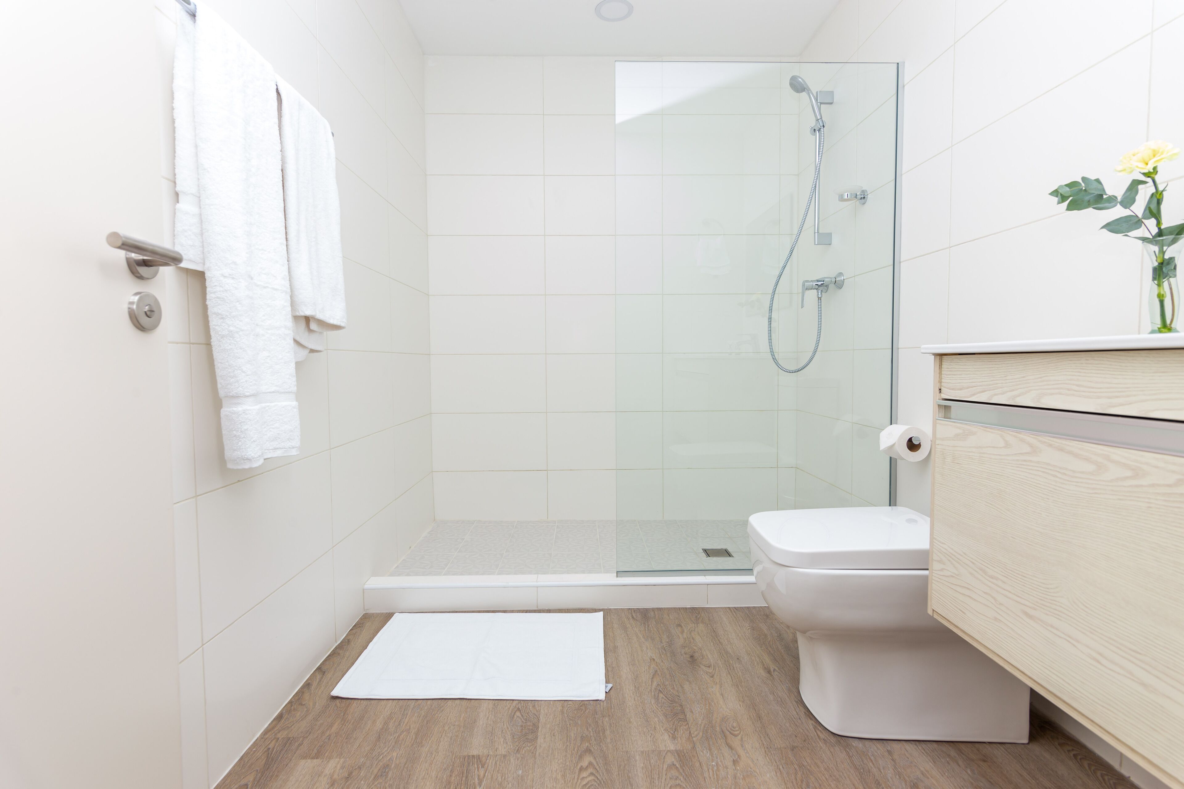 Ein modernes Badezimmer mit einer Duschkabine aus Glas, einer weißen Toilette und einem Holzbadezimmer-Möbelkorpus.