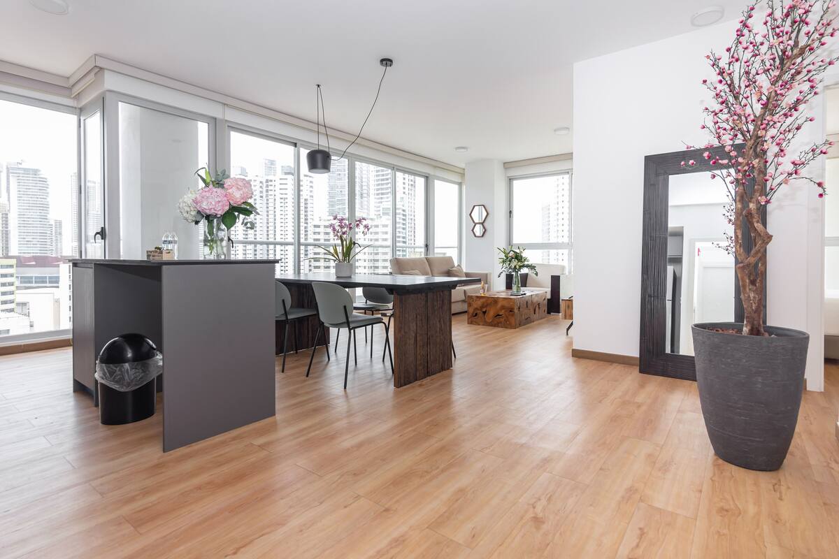 A modern kitchen with a central island, large windows, and a view of the city.