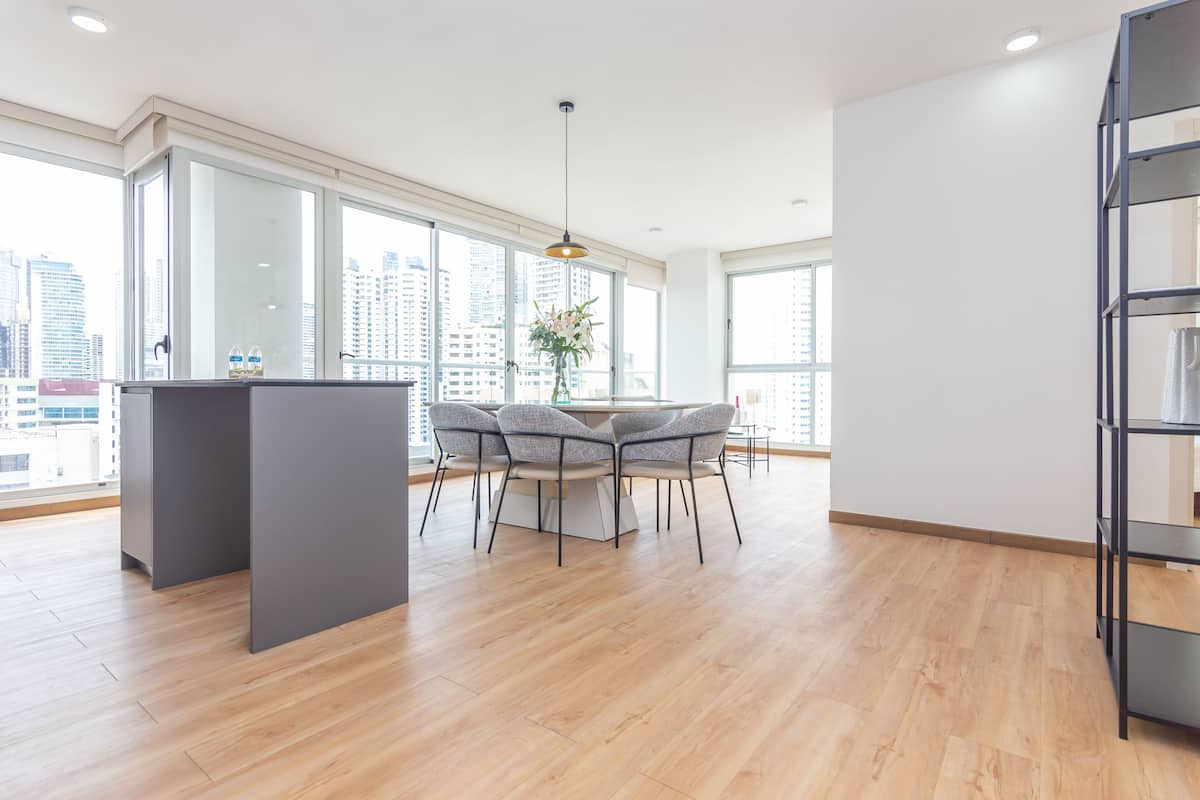 A spacious room with a dining area, large windows, and a view of the cityscape.