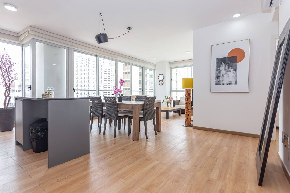A modern dining area with a wooden table and chairs, a small side table, and a potted plant.