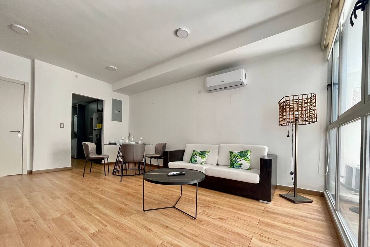 A modern living room with a sofa, coffee table, and dining area.