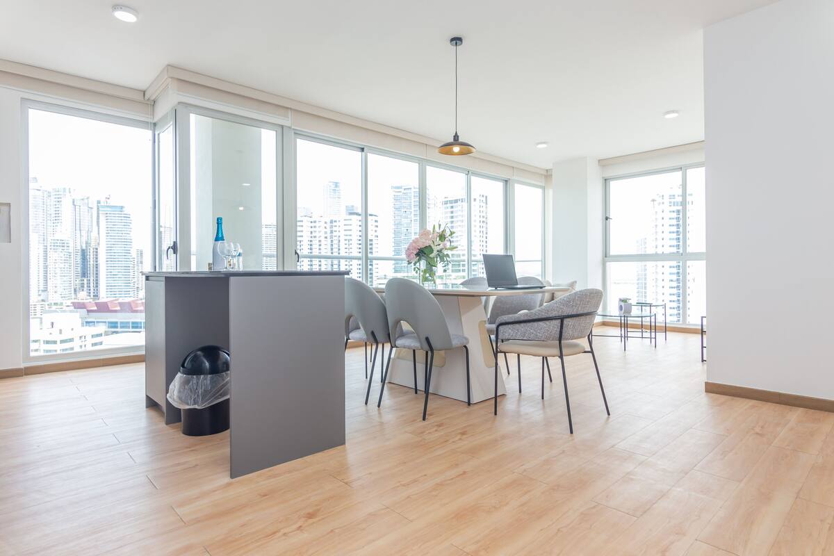 A modern kitchen with a dining area, large windows, and a city view.