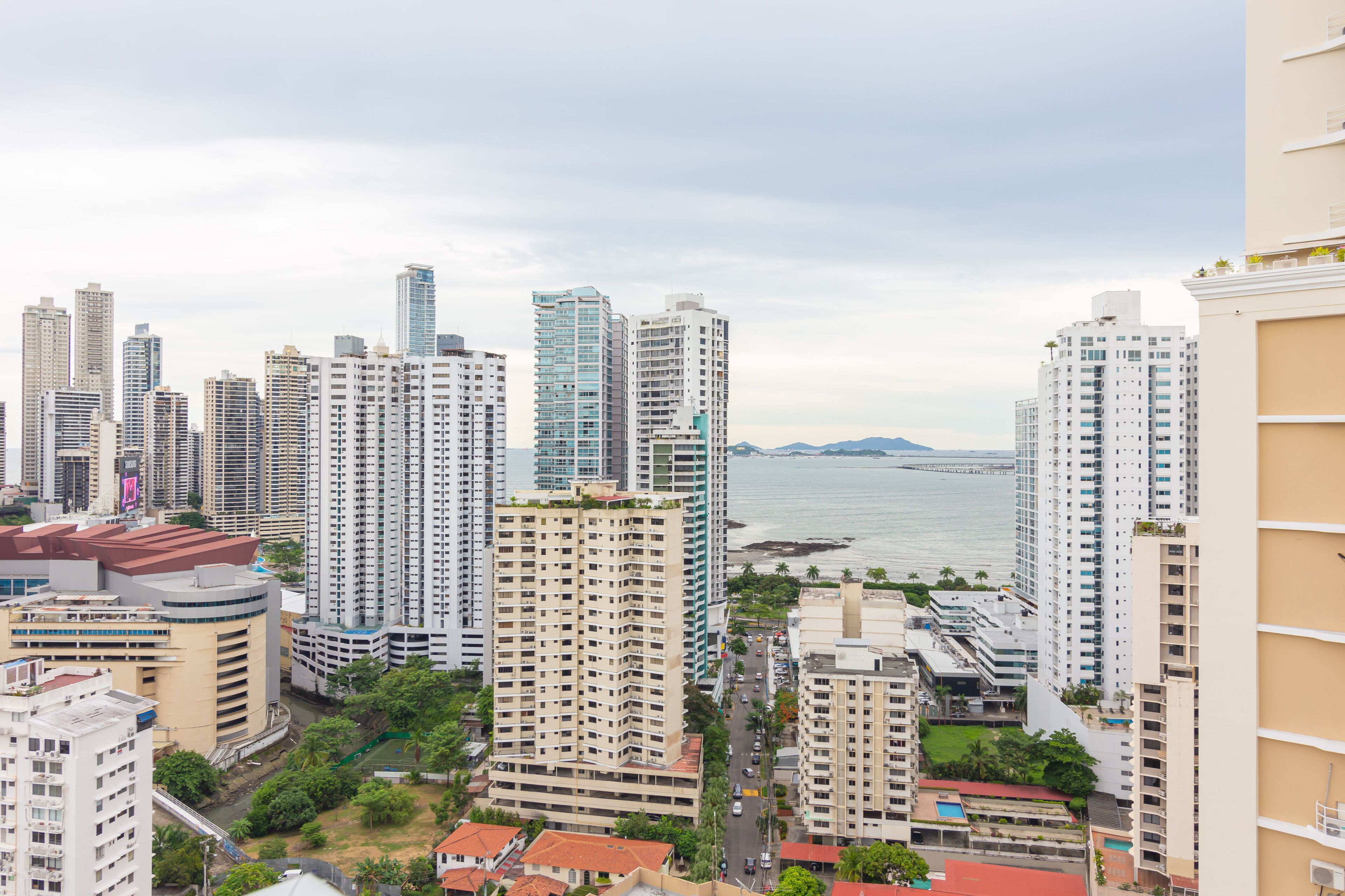 A high-rise urban area with multiple buildings, a body of water, and a distant mountain range.