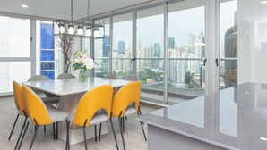 Een moderne eetruimte met een glazen tafel, gele stoelen en uitzicht over de stad.