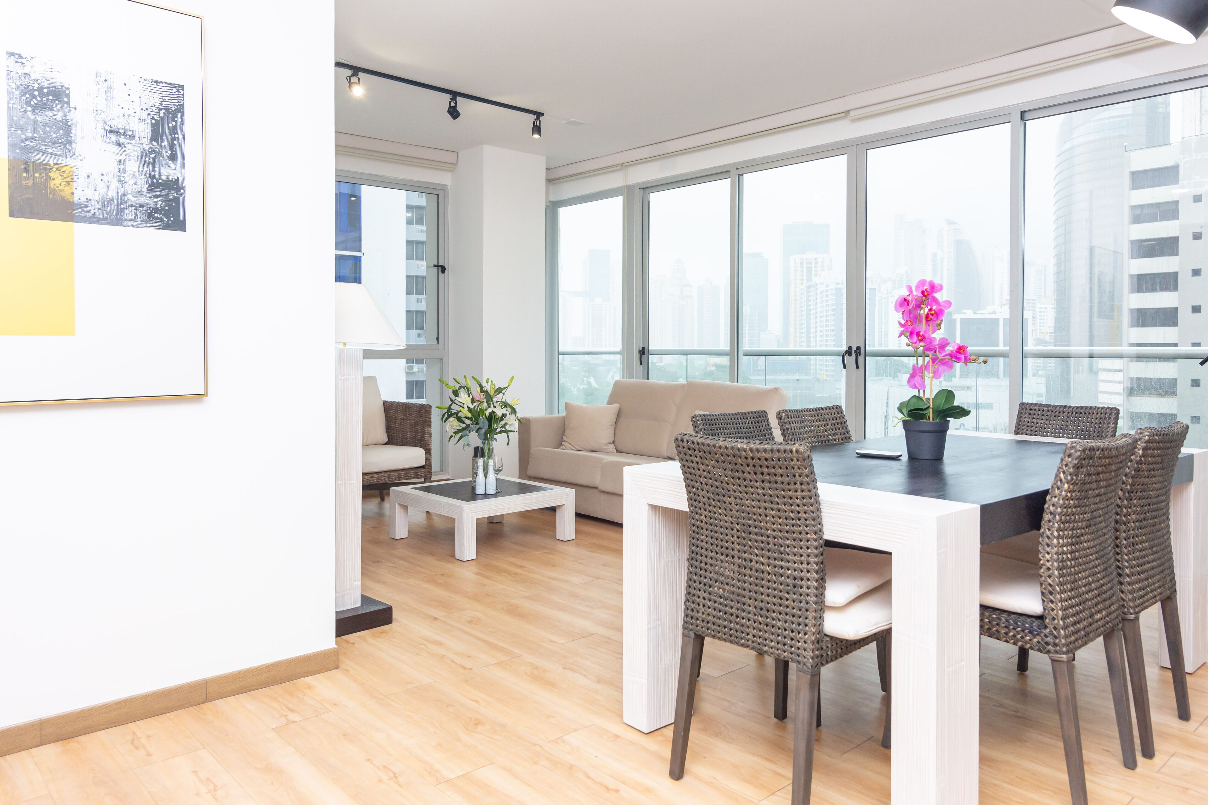Una sala de estar moderna con comedor, ventanas amplias y vistas a la ciudad.