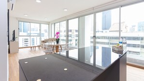 Een moderne keuken met een groot eiland, een eethoek met een ronde tafel, en grote ramen met uitzicht op de stad.
