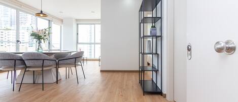 Una cocina moderna con comedor, suelo de madera, estantería empotrada y amplios ventanales con vistas a la ciudad.