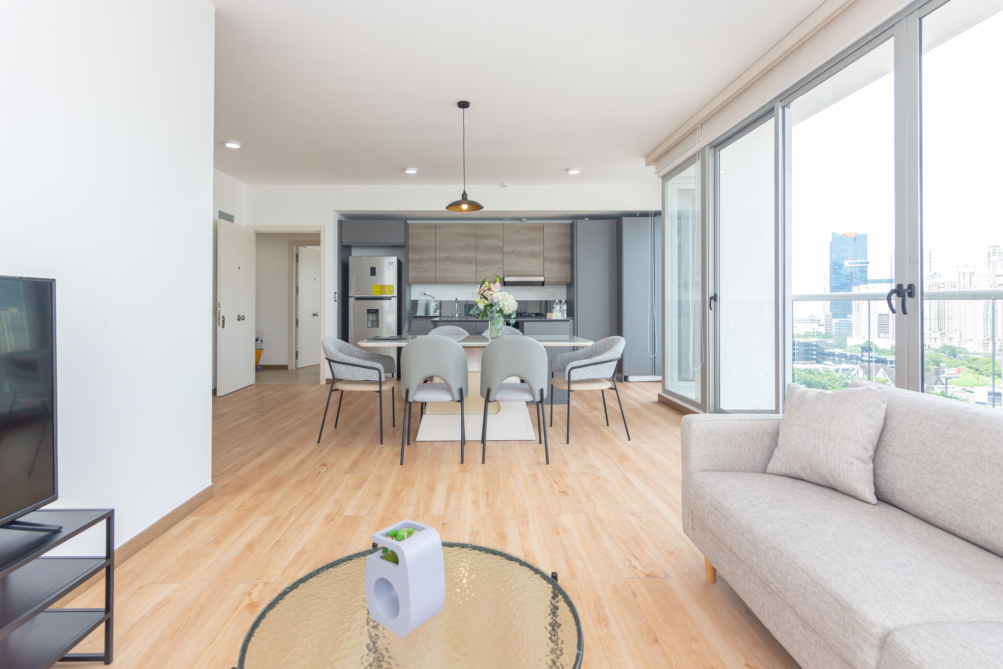 Un apartamento moderno con comedor, cocina y un amplio ventanal con vistas a la ciudad.