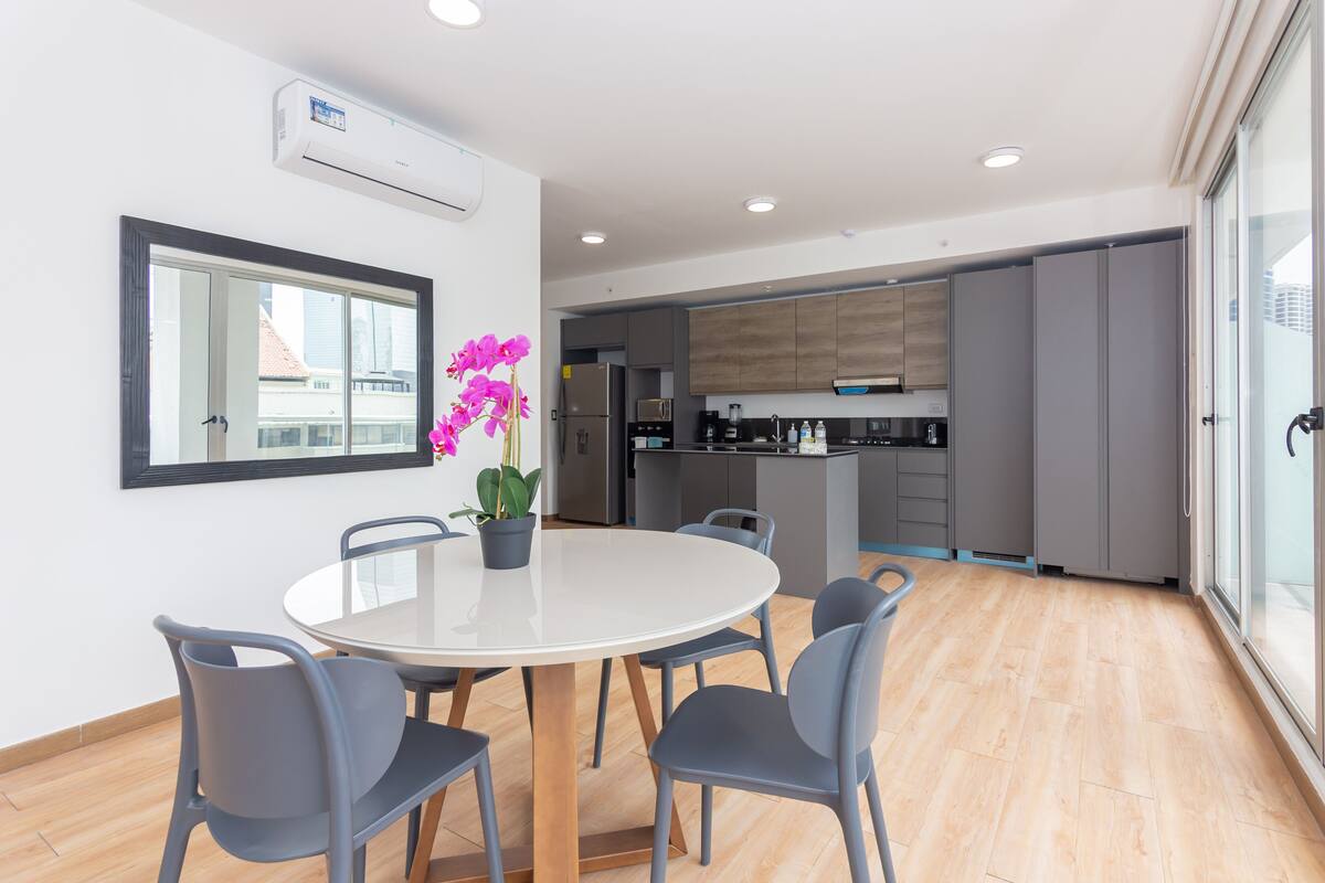 A modern kitchen with grey cabinets, a central island, and a built-in oven.
