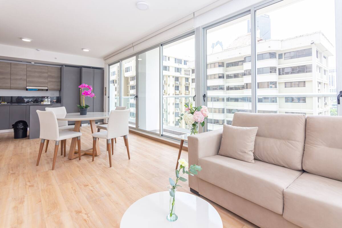 A modern living room with a sofa, dining table, chairs, and a coffee table.