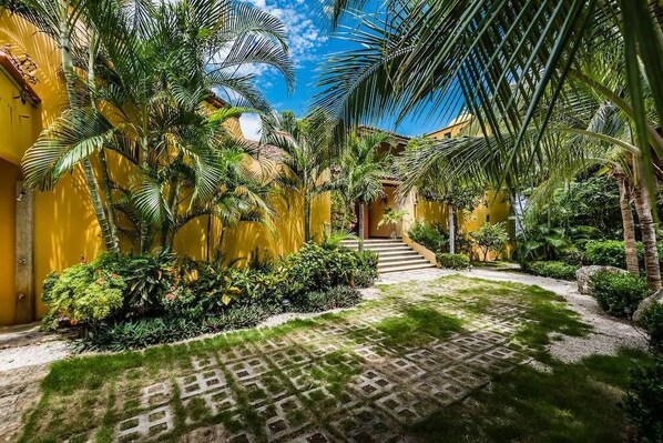 A courtyard with palm trees, a patterned walkway, and yellow walls.