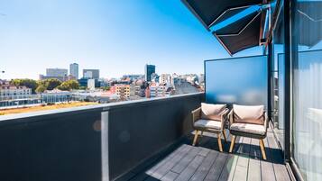 Un balcón con vistas a un paisaje urbano, con edificios modernos y un cielo despejado.