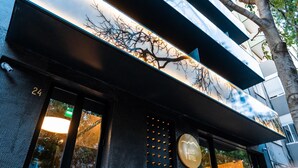 A hotel entrance with a large window displaying a tree silhouette against a sunset. - Hills Hotel Lisboa (Lisbon)