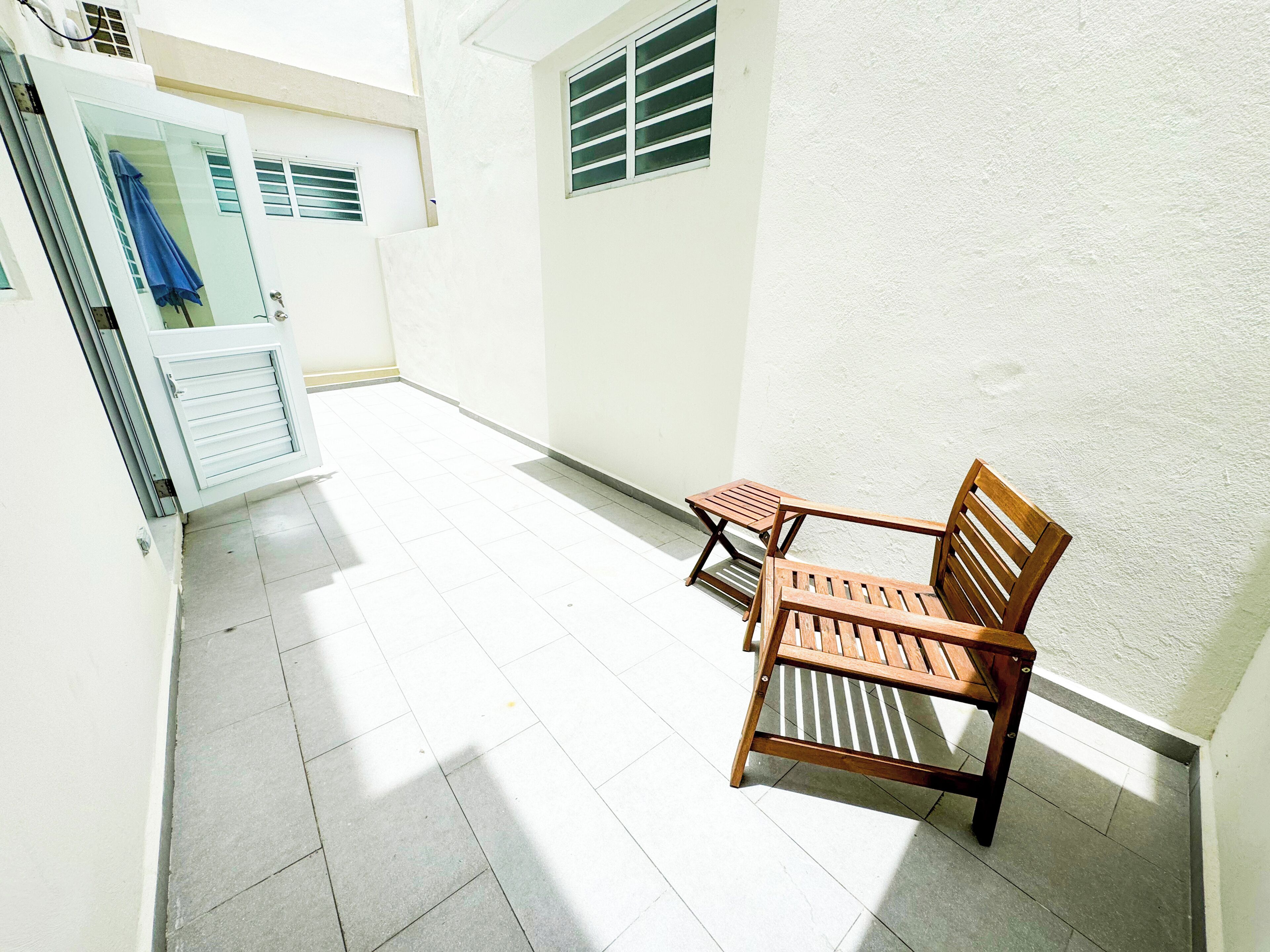 A clean, well-lit corridor with a tiled floor, a wooden bench, and a door with a towel hanging on it.