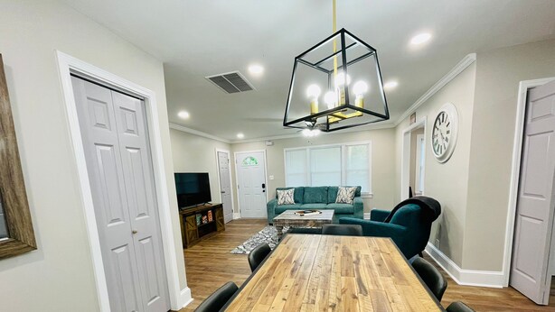 A spacious room with a wooden dining table, a green sofa, and a television.